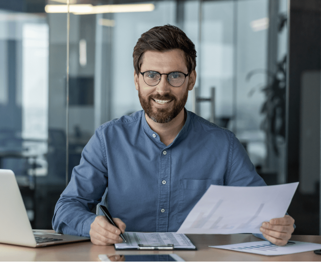 Man smiling while holding documents in office.