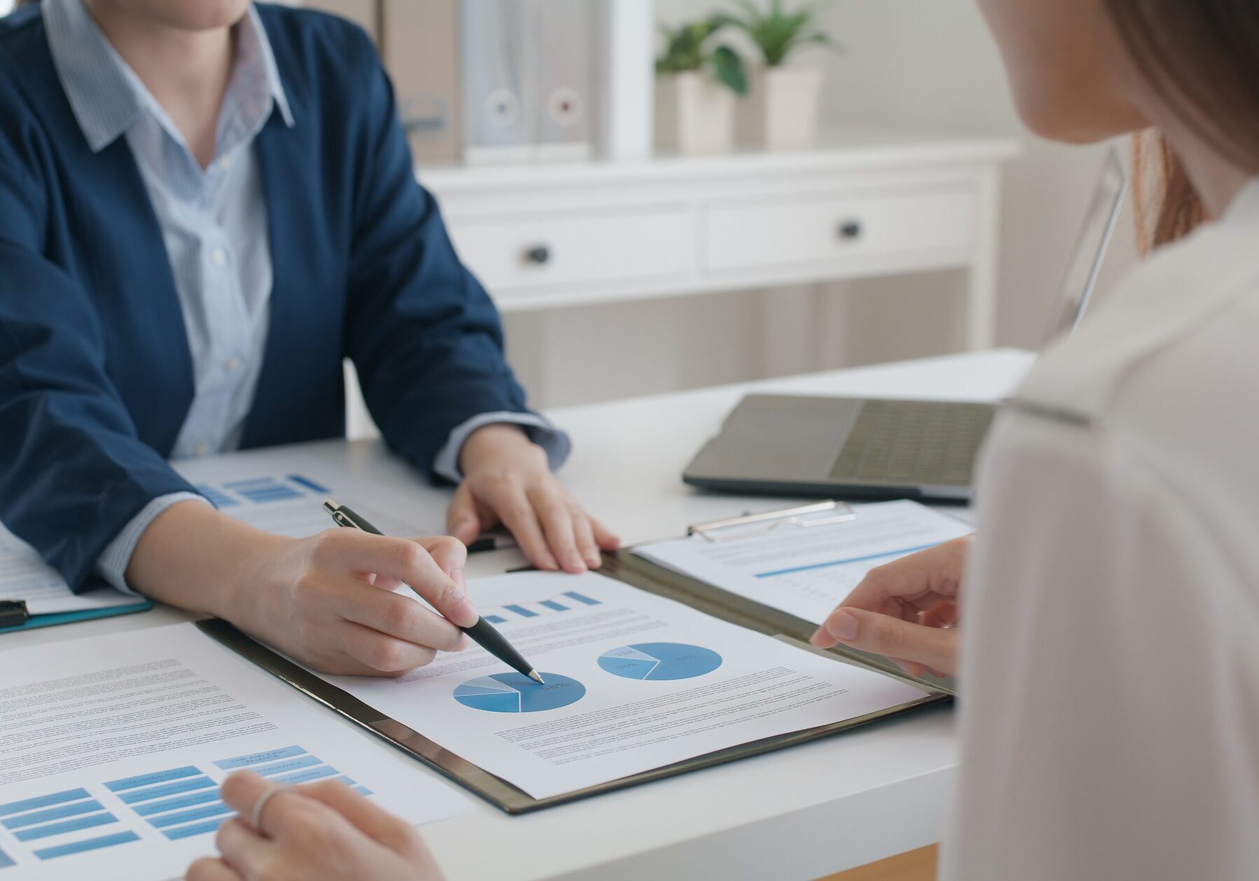 Two people discussing financial charts at desk.