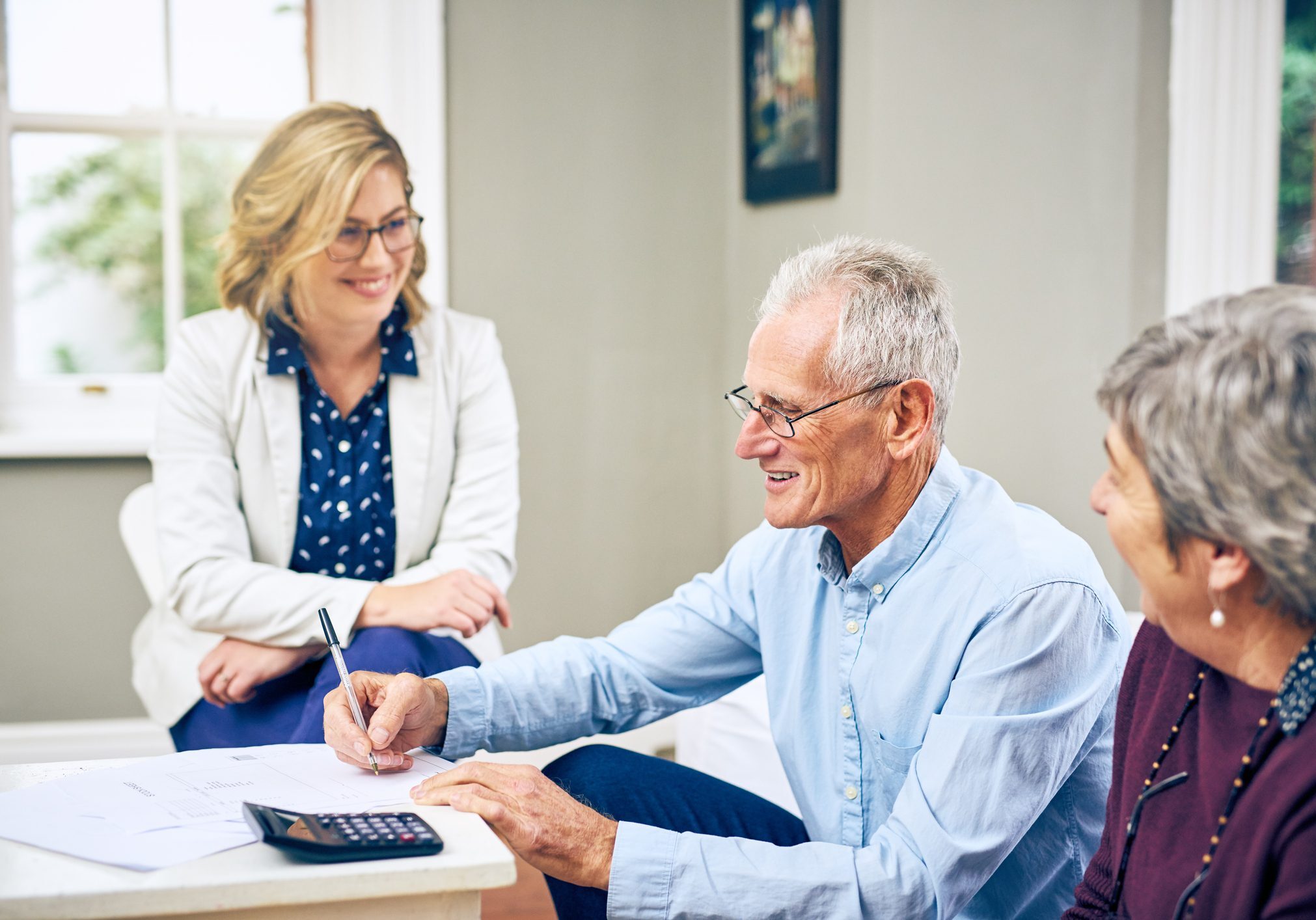 Elderly couple signing documents with advisor.